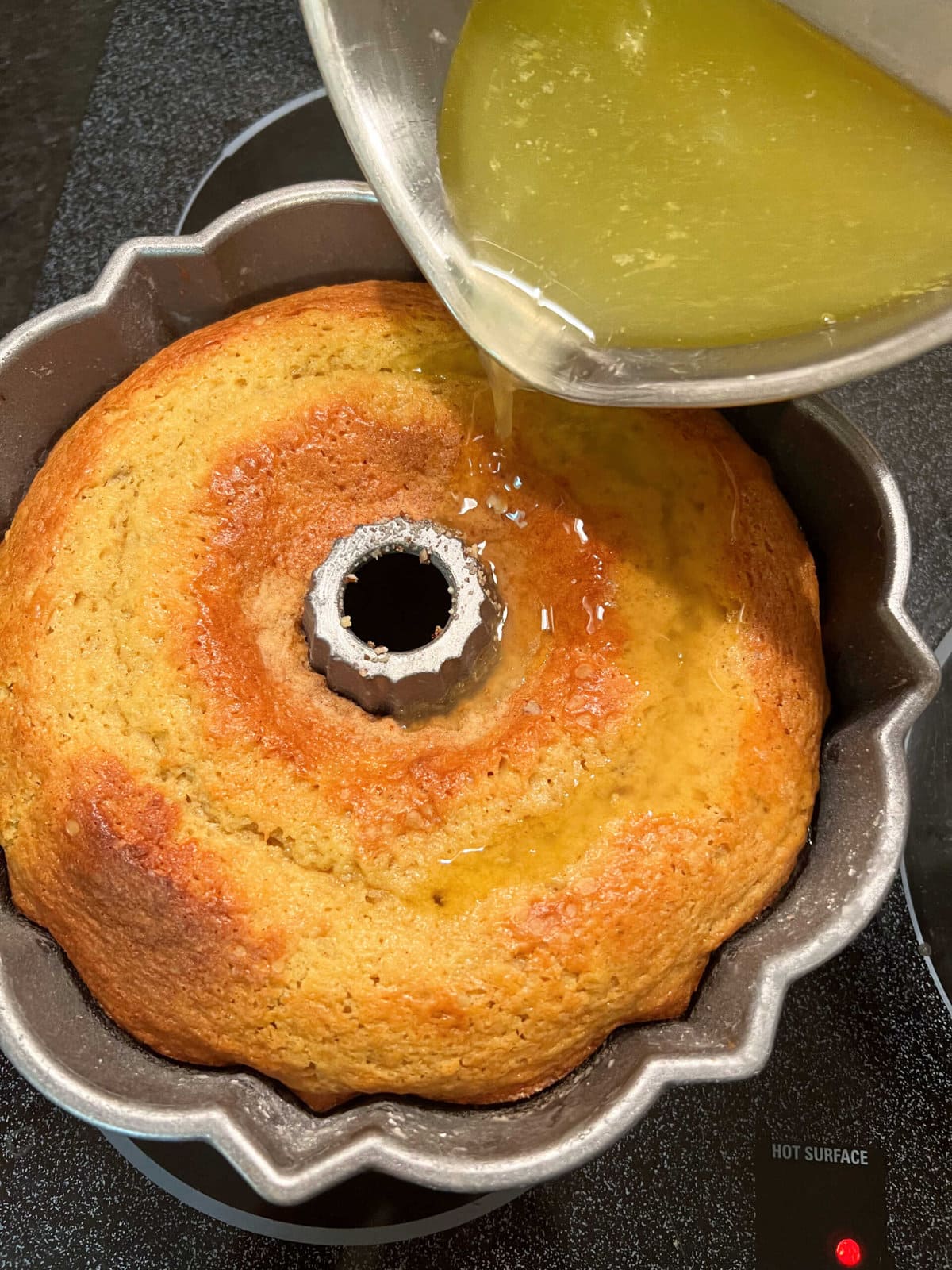 Pouring the rum glaze over the freshly baked cake.