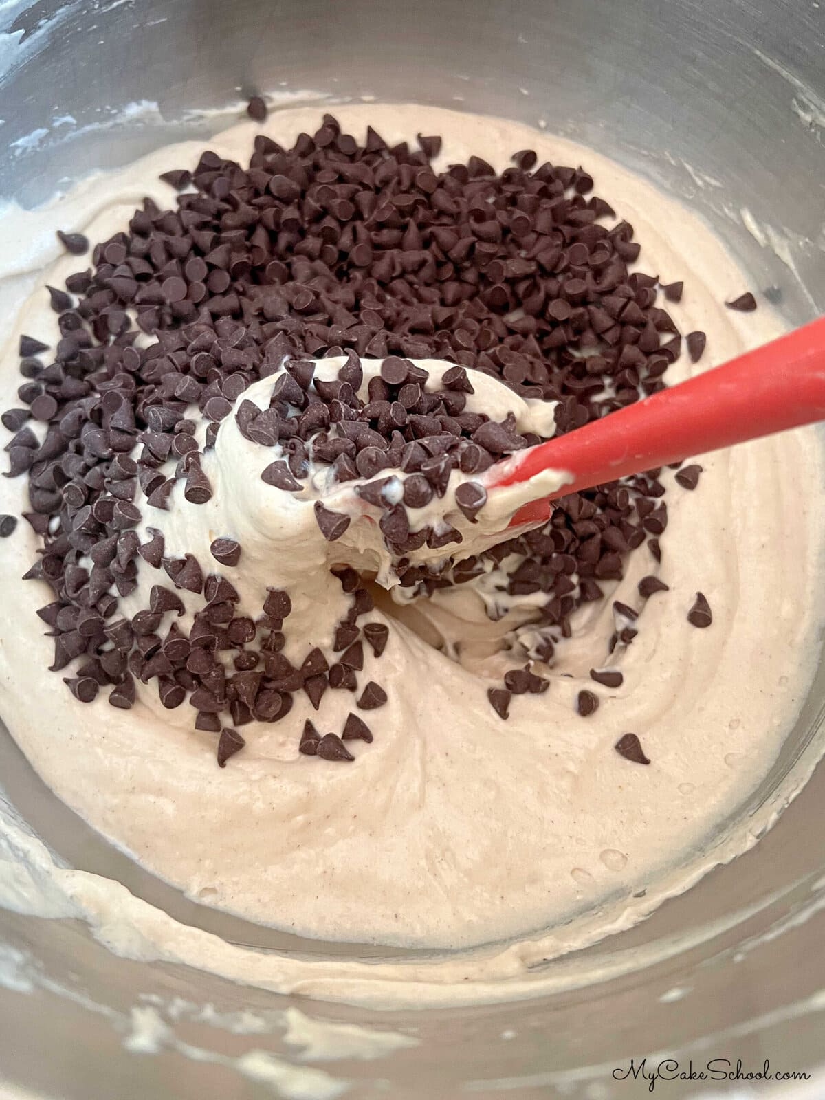 Folding mini chocolate chips into the cupcake batter.