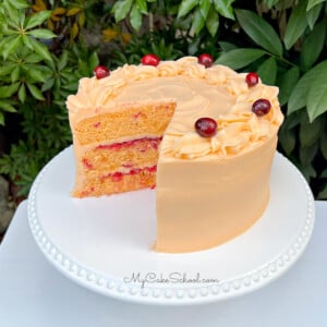 Cranberry Orange Cake, sliced, on a white cake pedestal.