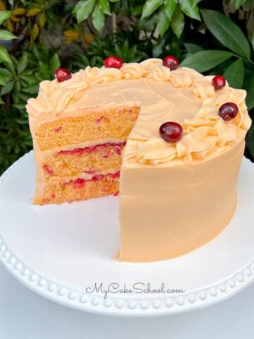 Cranberry Orange Cake, sliced, on a white cake pedestal.