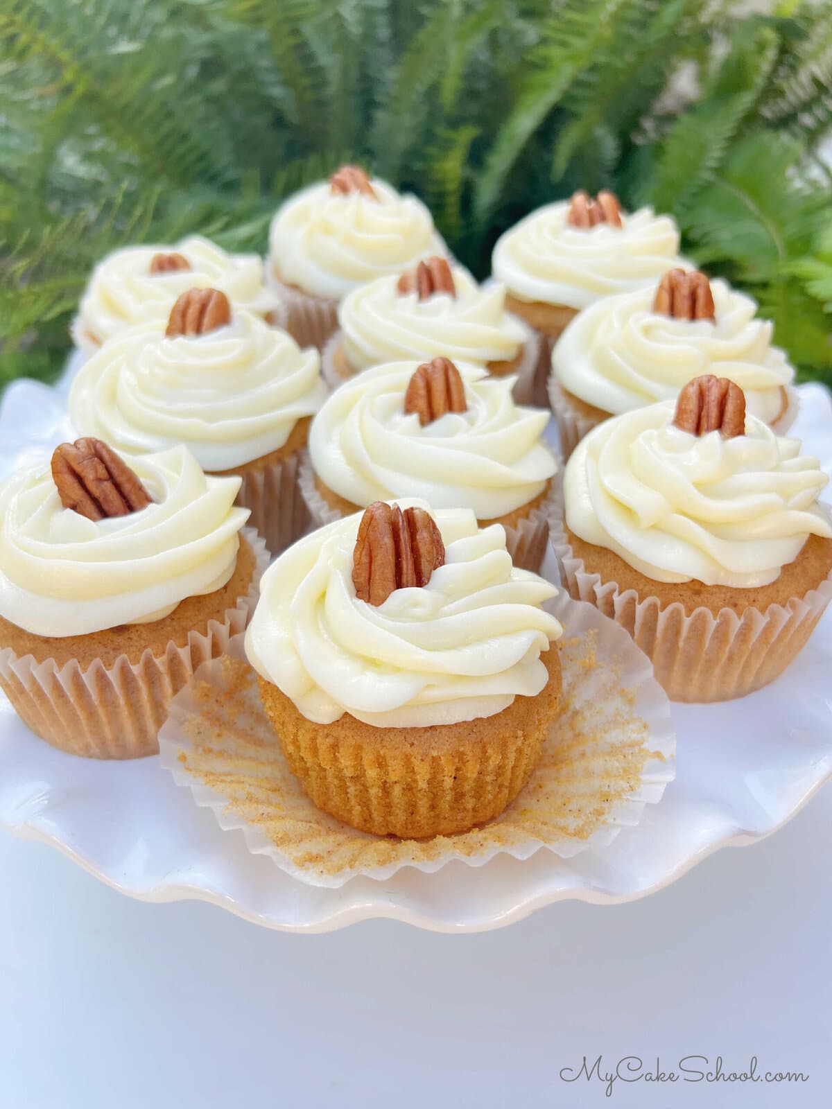 Homemade Sweet Potato Cupcakes, frosted with cream cheese frosting, on a cake pedestal.