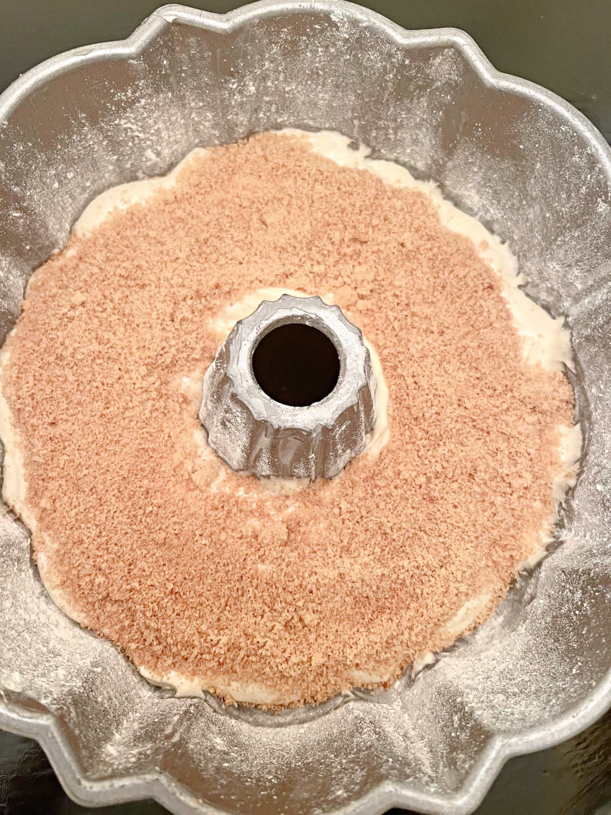 Half of cake batter in the bundt pan, sprinkled with the mixture of cinnamon and brown sugar.