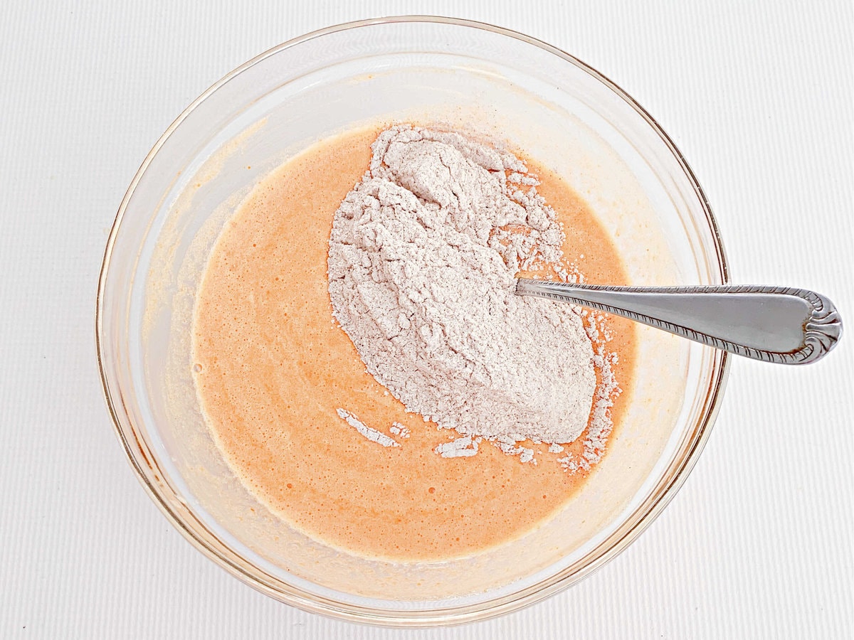 Folding dry mixture into wet mixture for pumpkin roll cake.