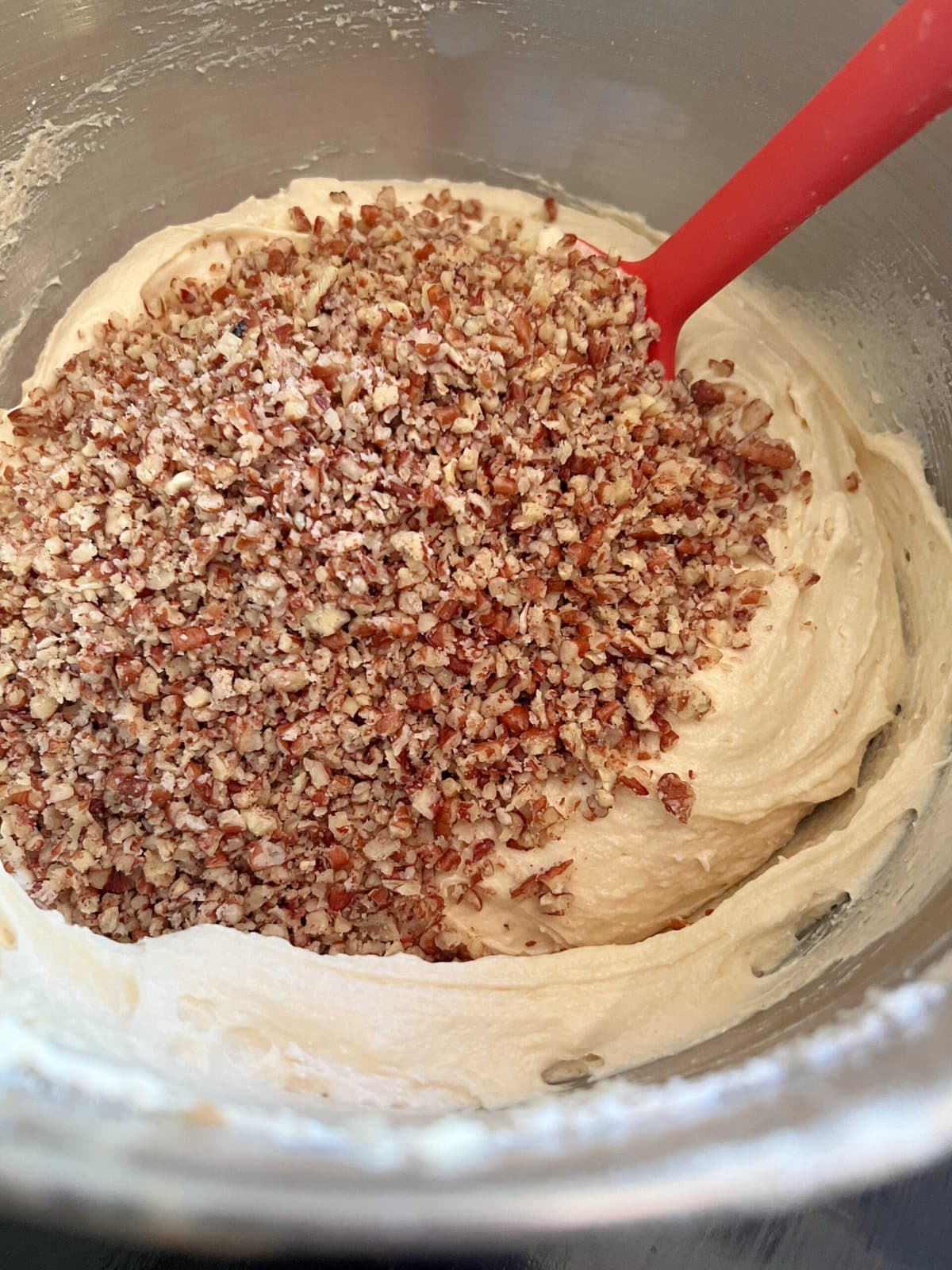 Stirring chopped buttered pecans into cake batter.