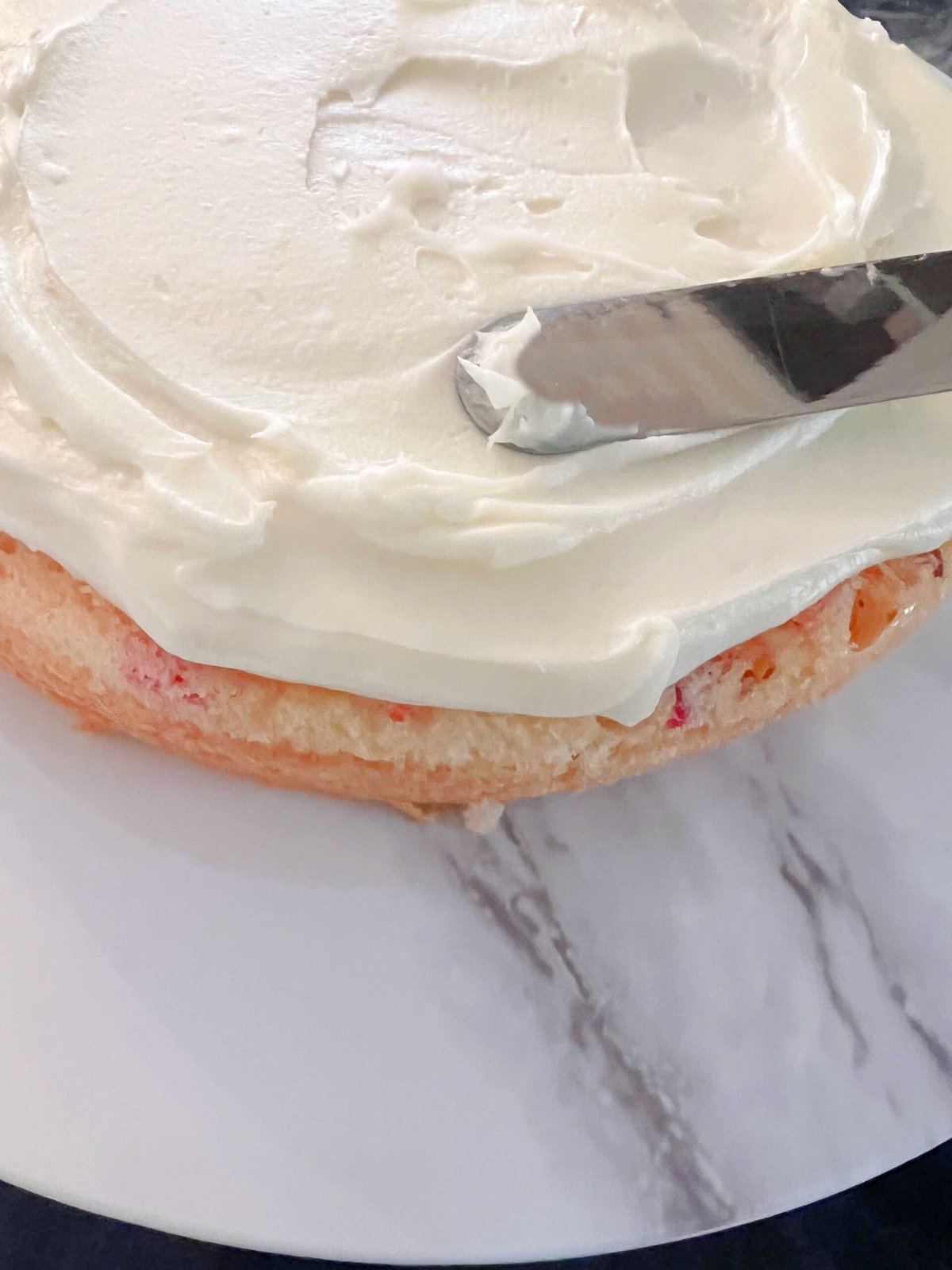 Spreading cherry-glazed cake layer with Almond Cream Cheese Frosting. 