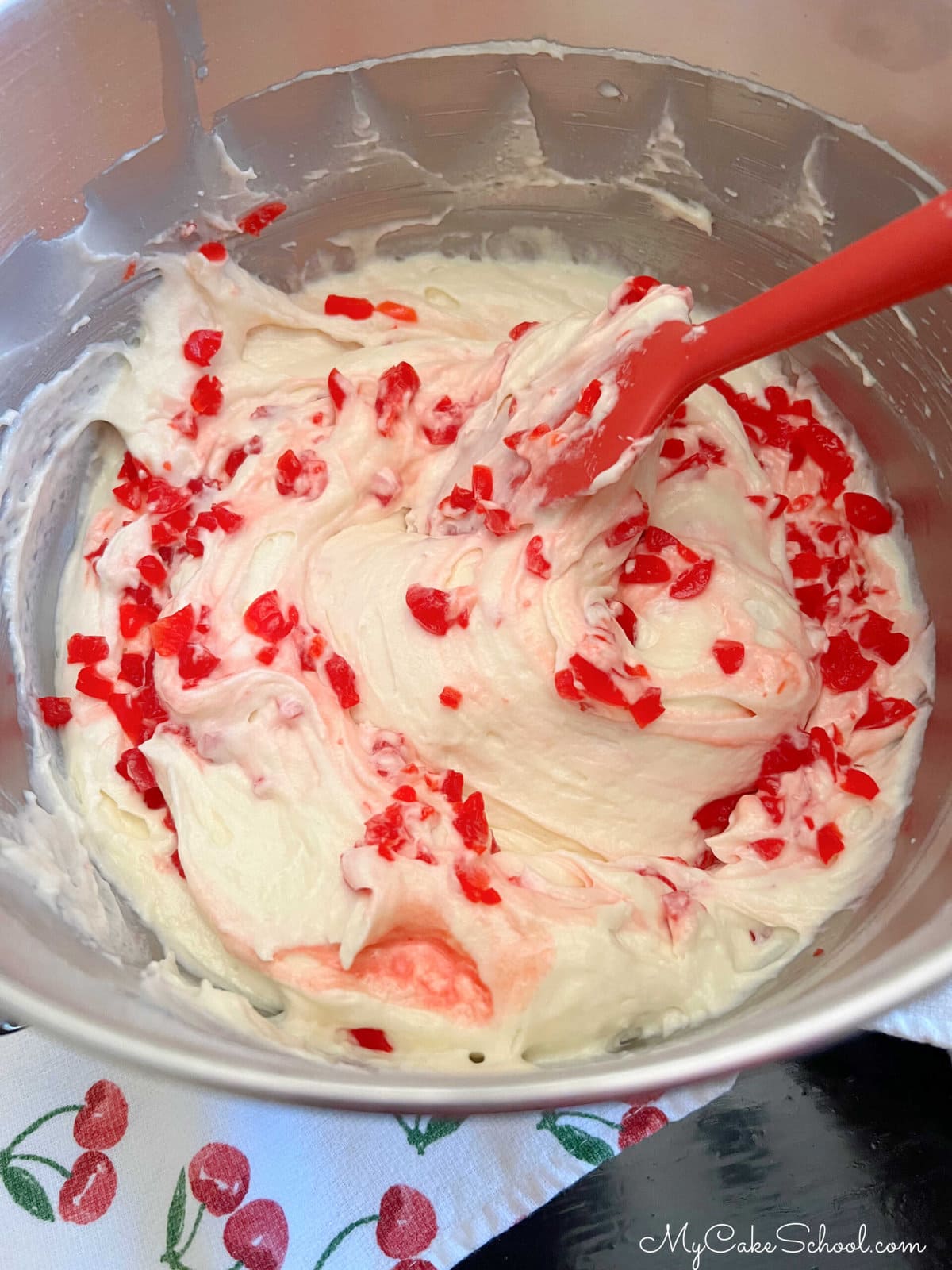 Folding maraschino cherries into the cake batter.