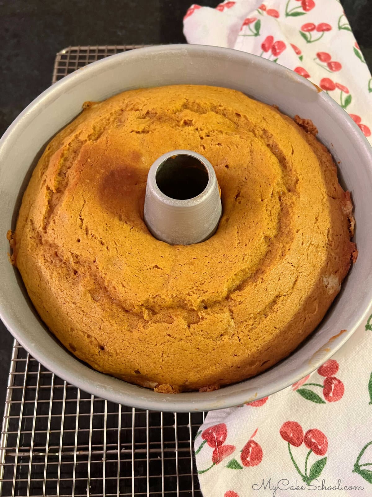 Freshly baked Pumpkin Bundt Cake in cake pan, cooling on wire rack.
