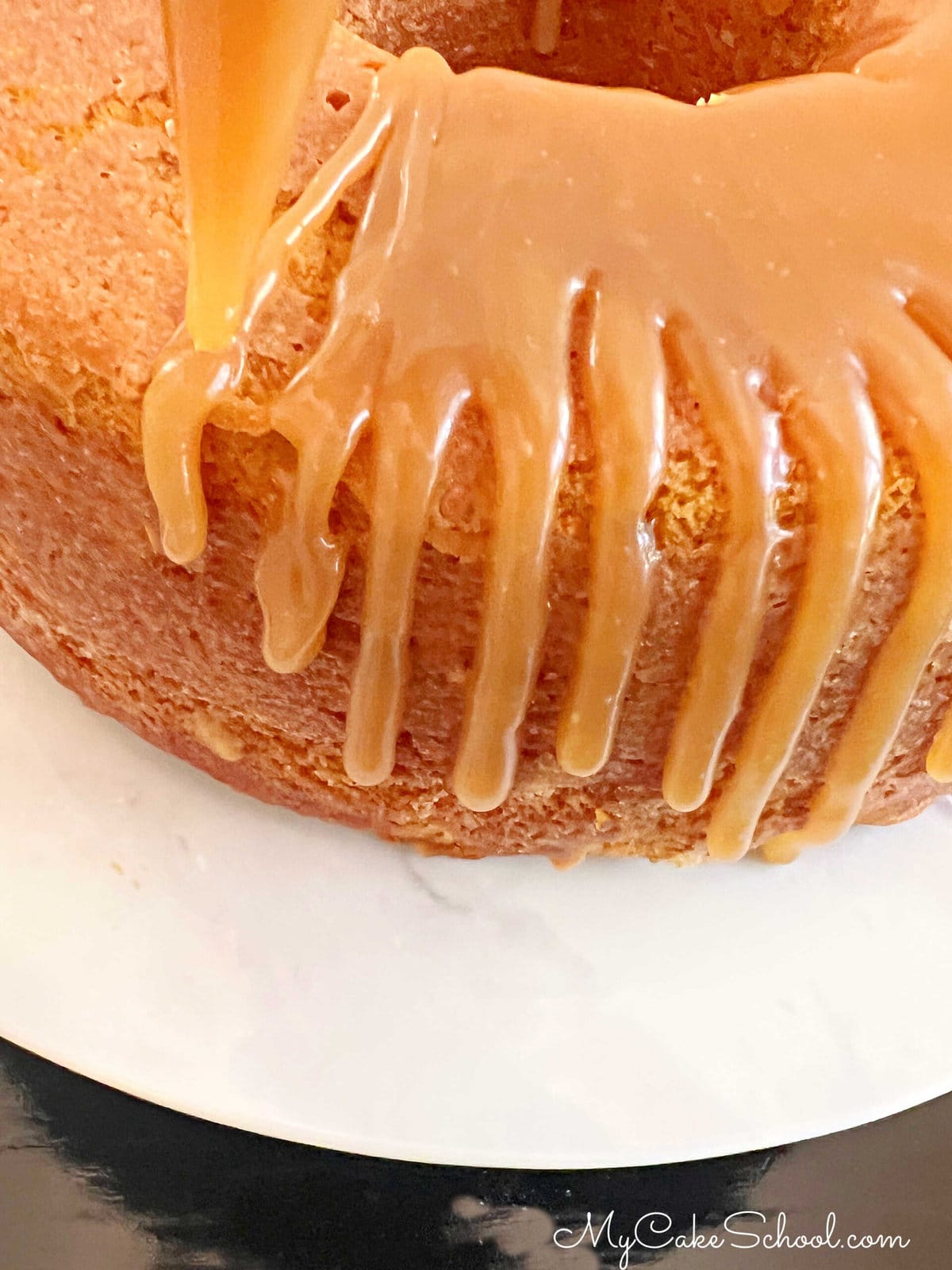 Applying caramel glaze to the pumpkin bundt cake with a disposable piping bag.