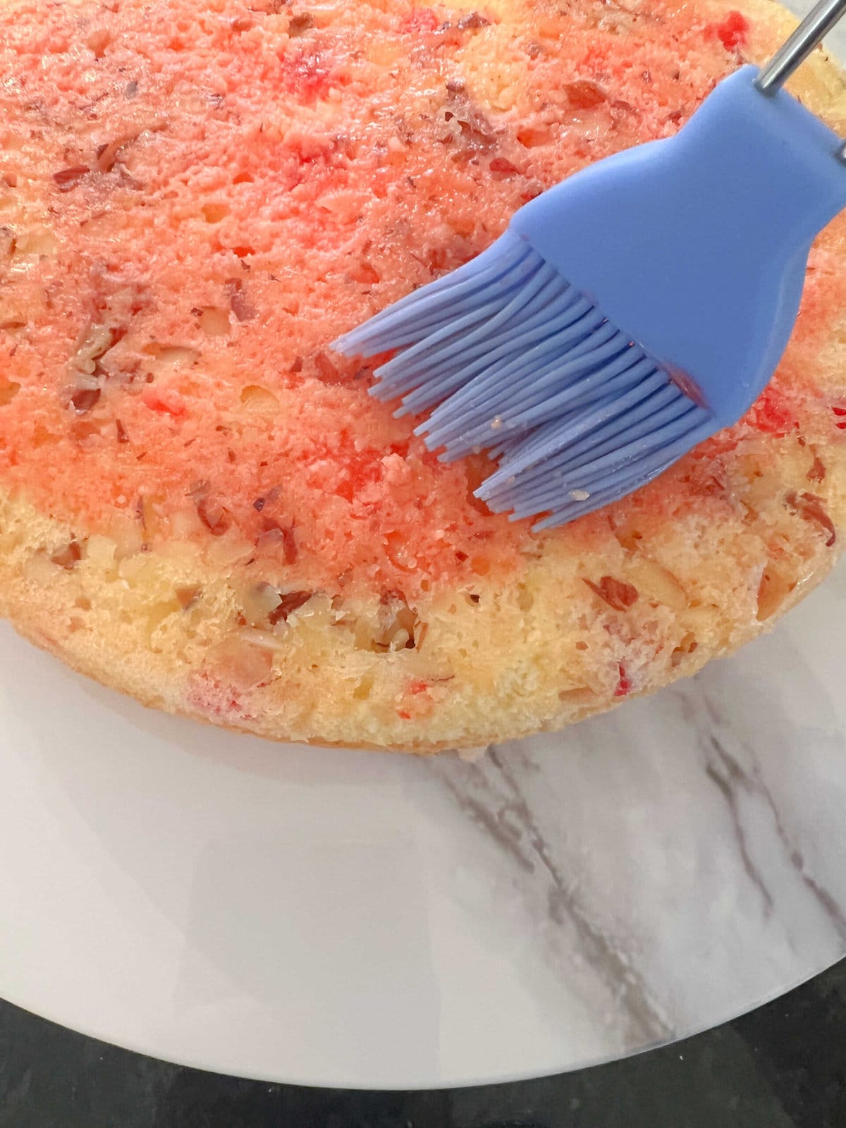 Brushing cake layer with cherry juice.