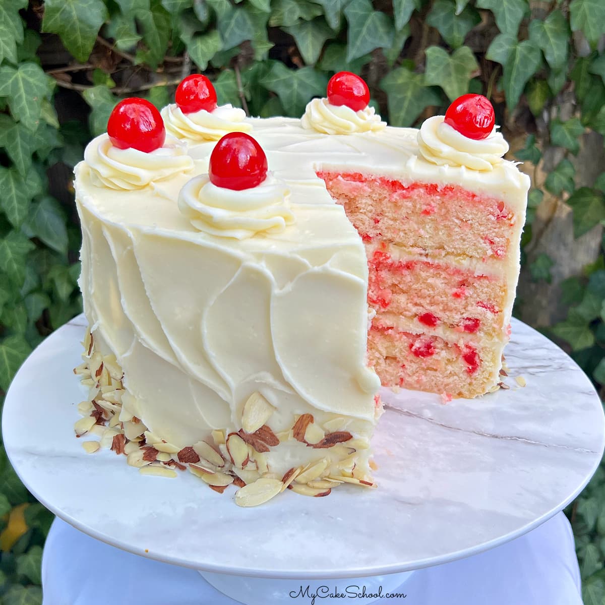 Sliced Cherry Almond Cake on a white pedestal.