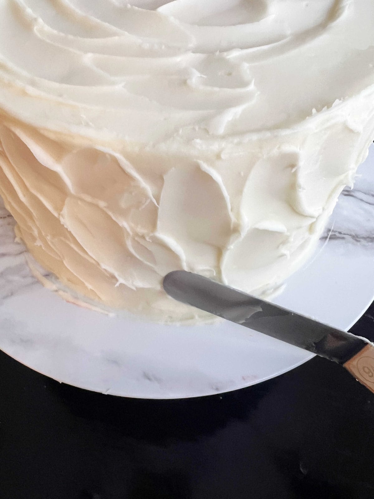 Frosting the Cherry Almond Cake using an offset spatula to create texture.