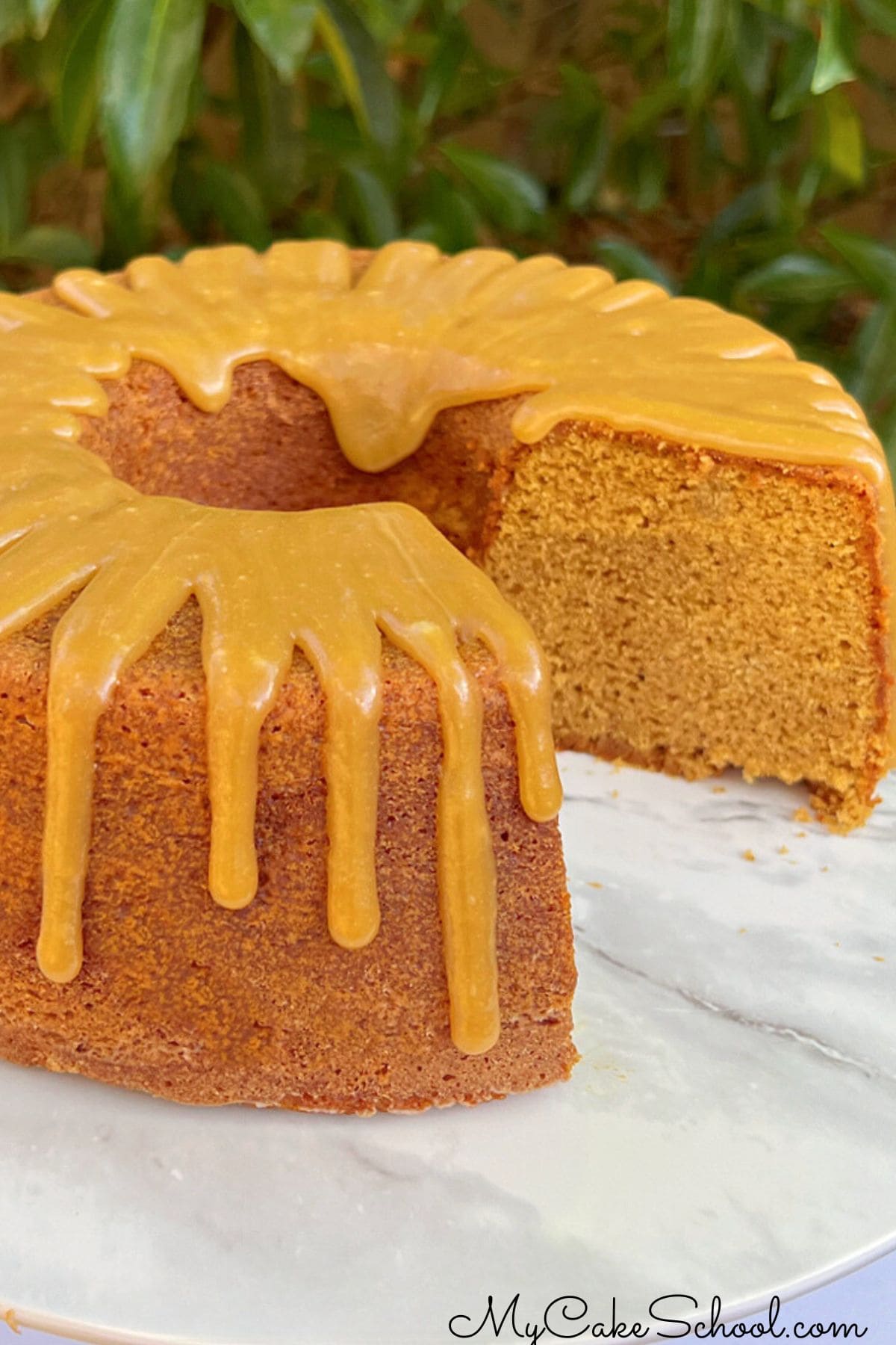 Sliced gingerbread bundt cake on cake pedestal with caramel glaze.