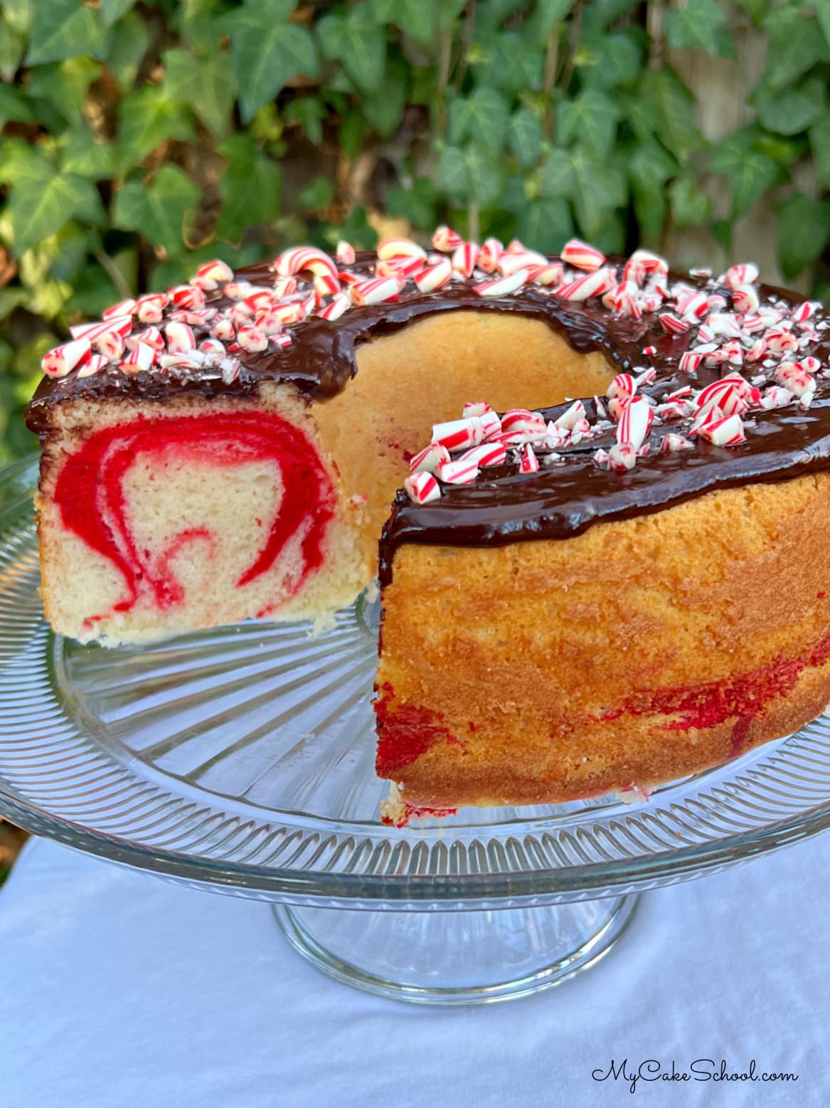 Sliced Peppermint Bundt Cake on a pedestal with chocolate glaze.