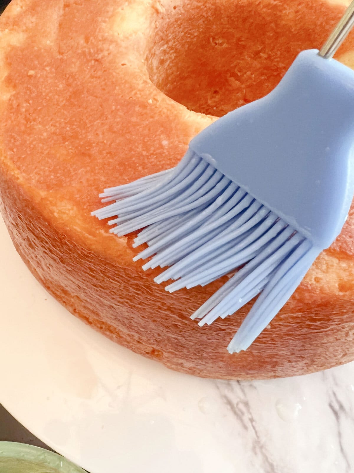 Brushing the pineapple pound cake with pineapple simple syrup, using a silicone brush.