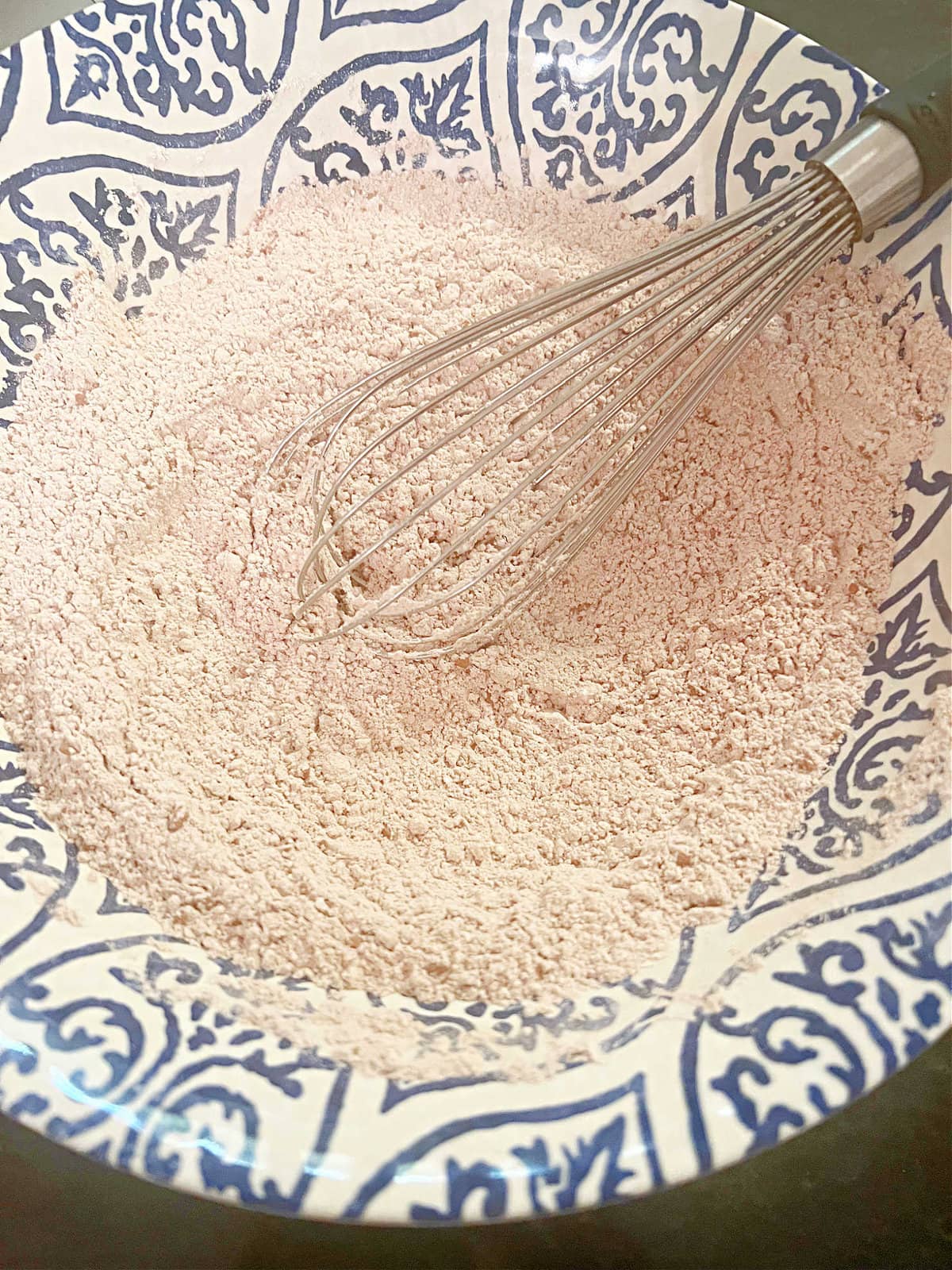 Dry ingredients in a bowl with a whisk.