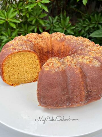 Moist Eggnog Rum Cake, sliced, on a white pedestal.