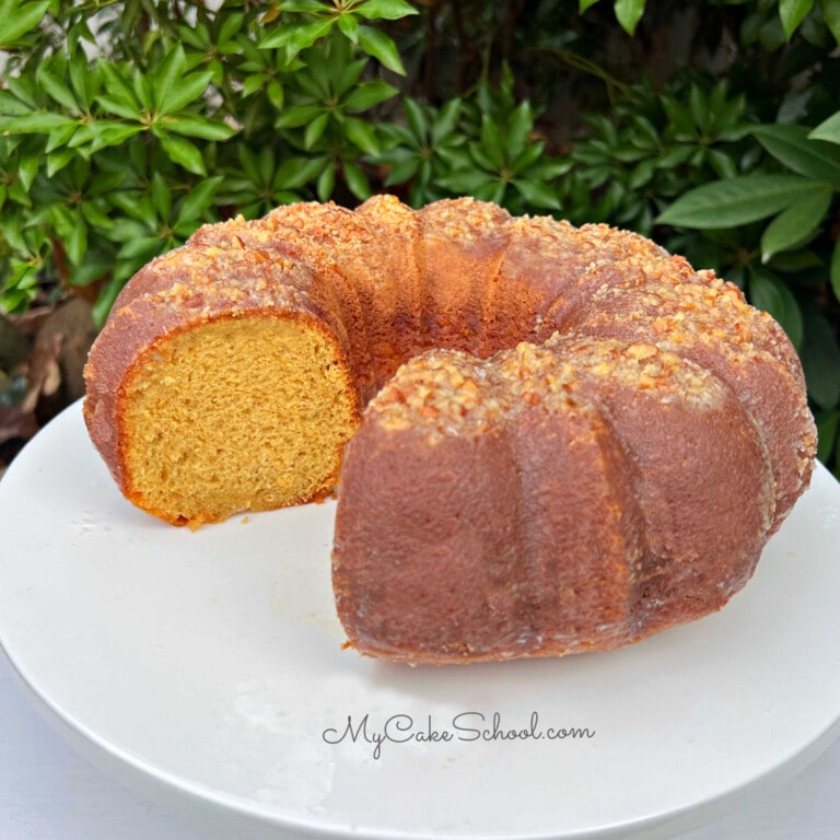 Moist Eggnog Rum Cake, sliced, on a white pedestal.