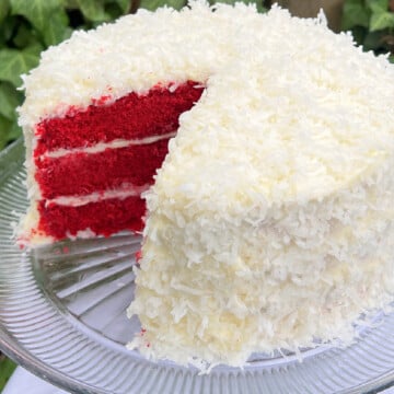 Sliced red velvet coconut cake layers on a cake pedestal.
