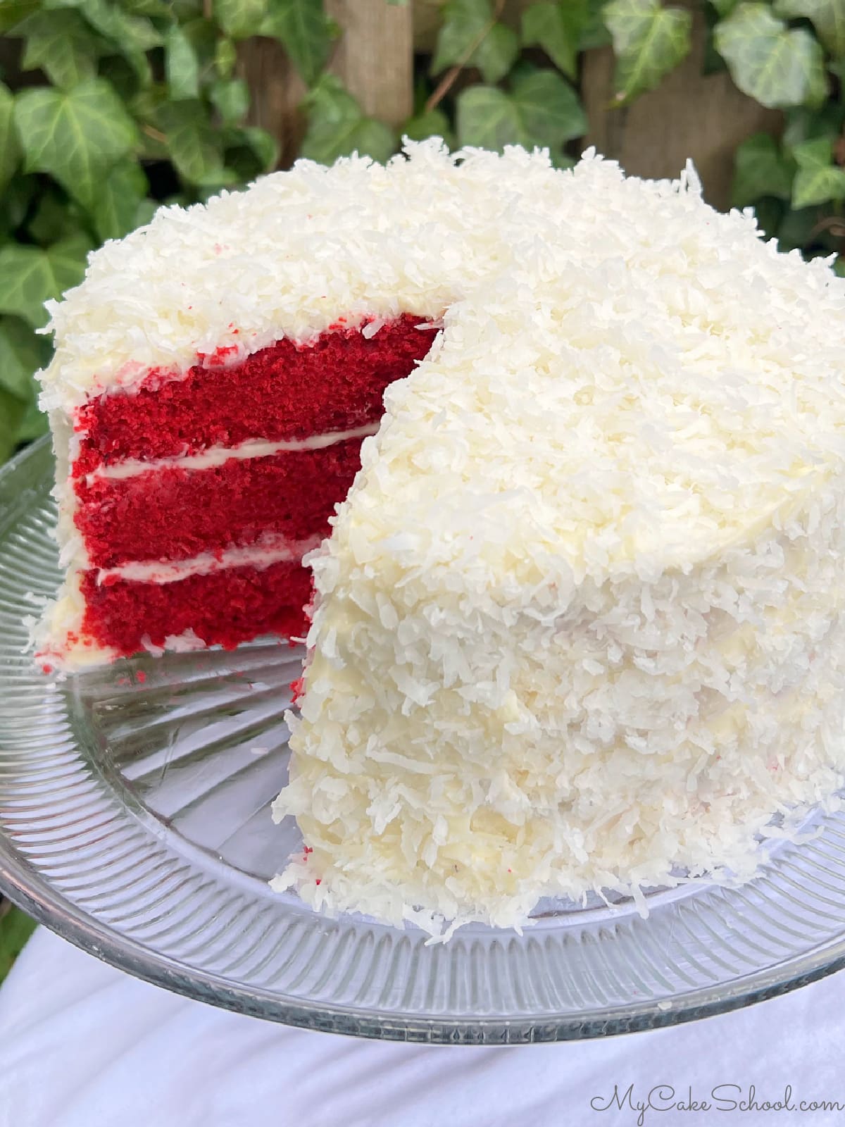 Sliced red velvet coconut cake layers on a cake pedestal.