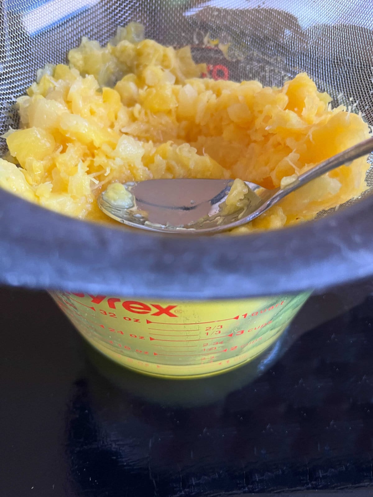 Pressing pineapple through strainer.