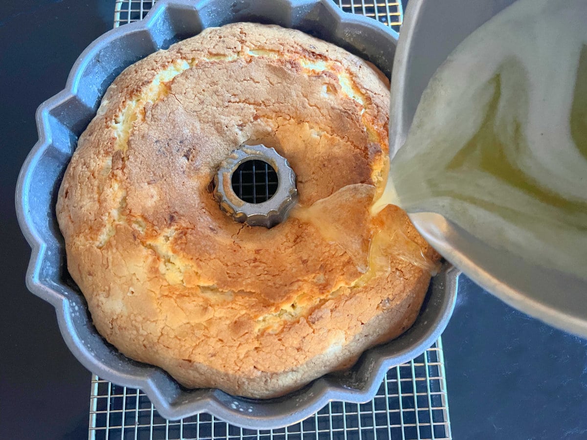 Pouring rum glaze over freshly baked pina colada pound cake, still in pan.