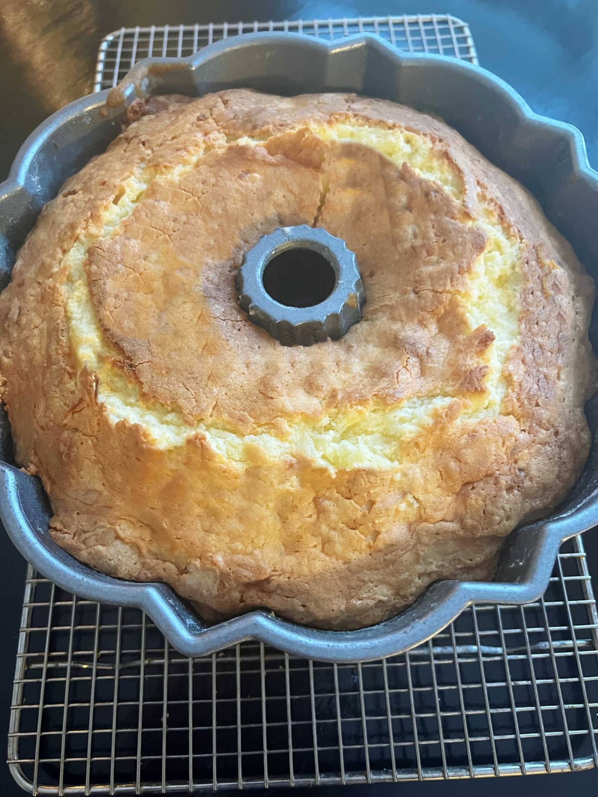 Freshly baked Pineapple Coconut Cake in the pan, on a cooling rack.