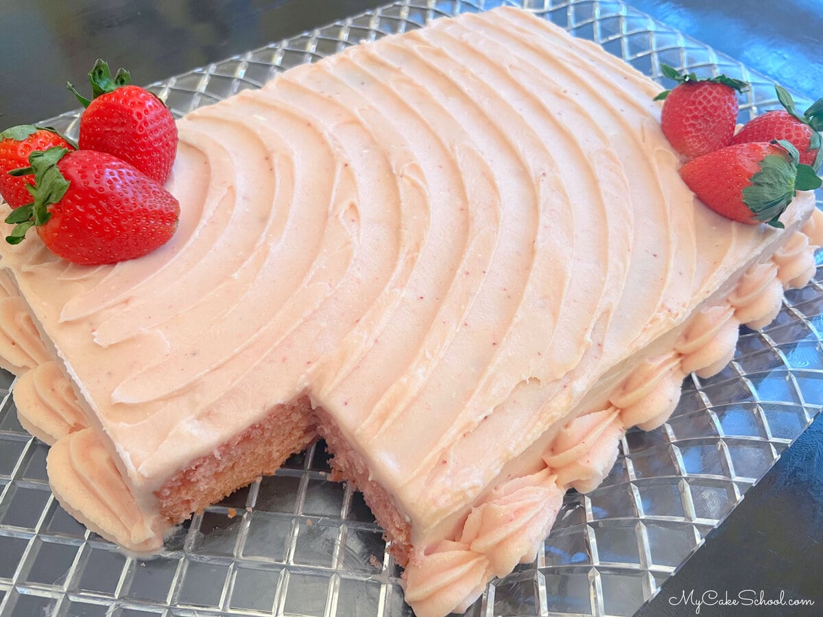 Sliced Strawberry Sheet Cake on clear cake platter.