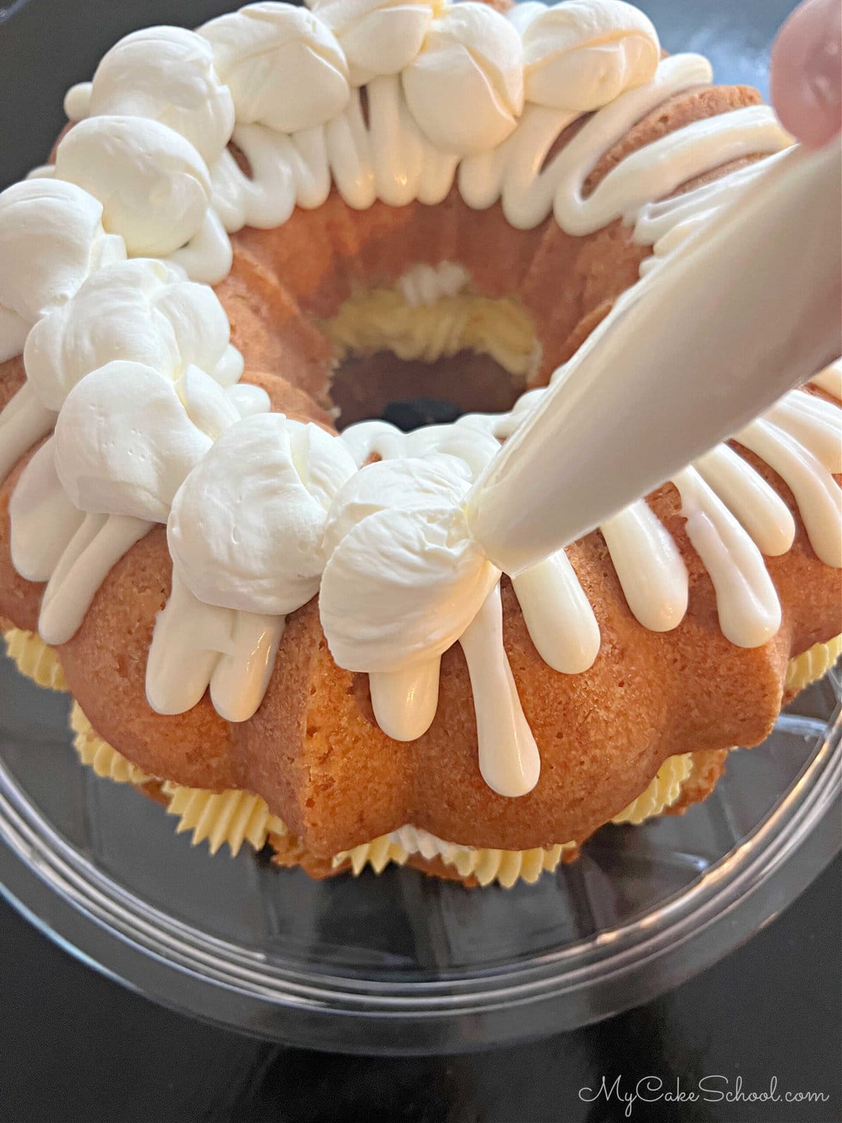 Adding whipped cream on top of the cream cheese glaze for decoration.