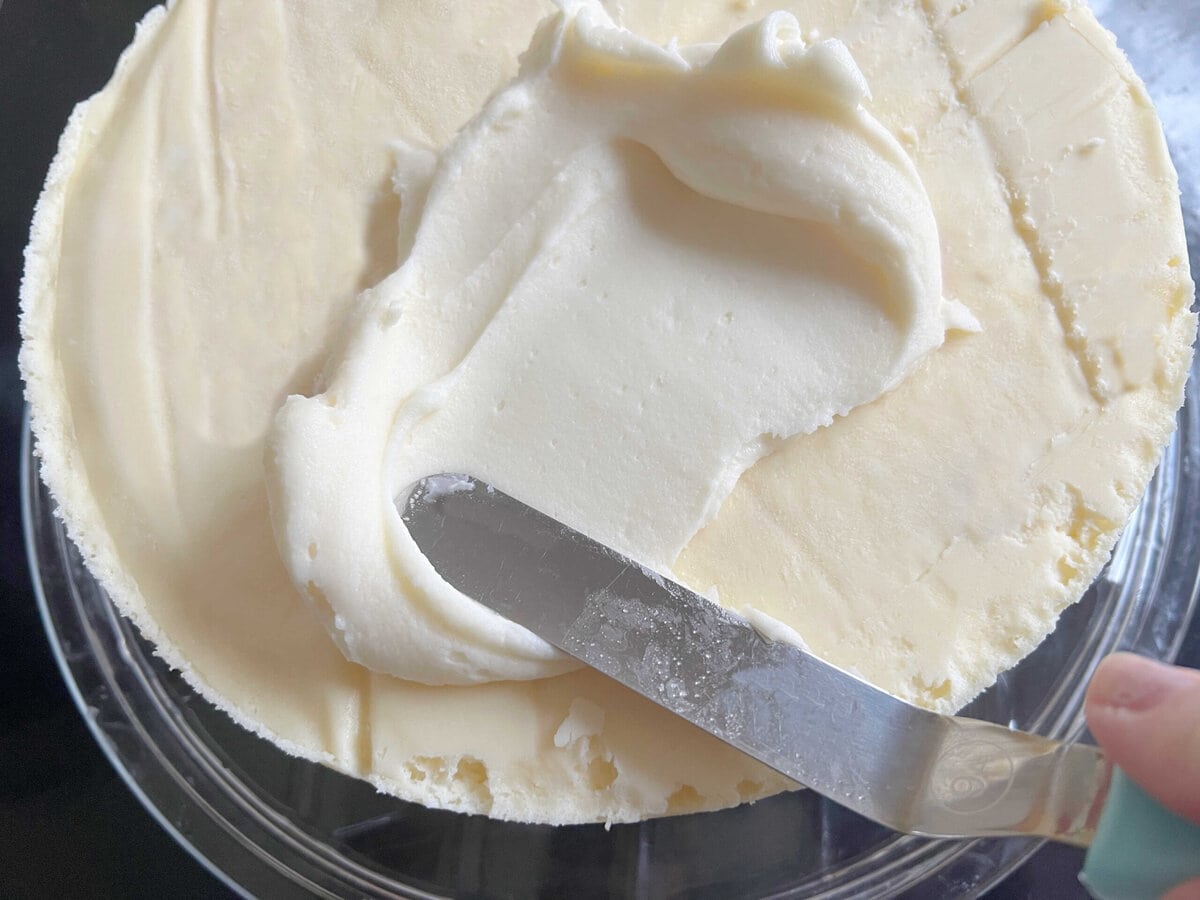 Spreading cheesecake layer with cream cheese frosting.