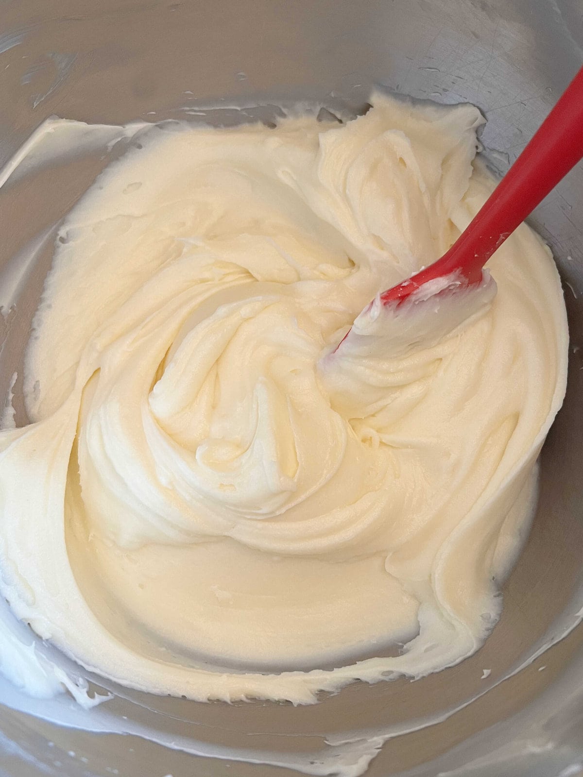 Cream Cheese Frosting, in a mixing bowl with red spatula.