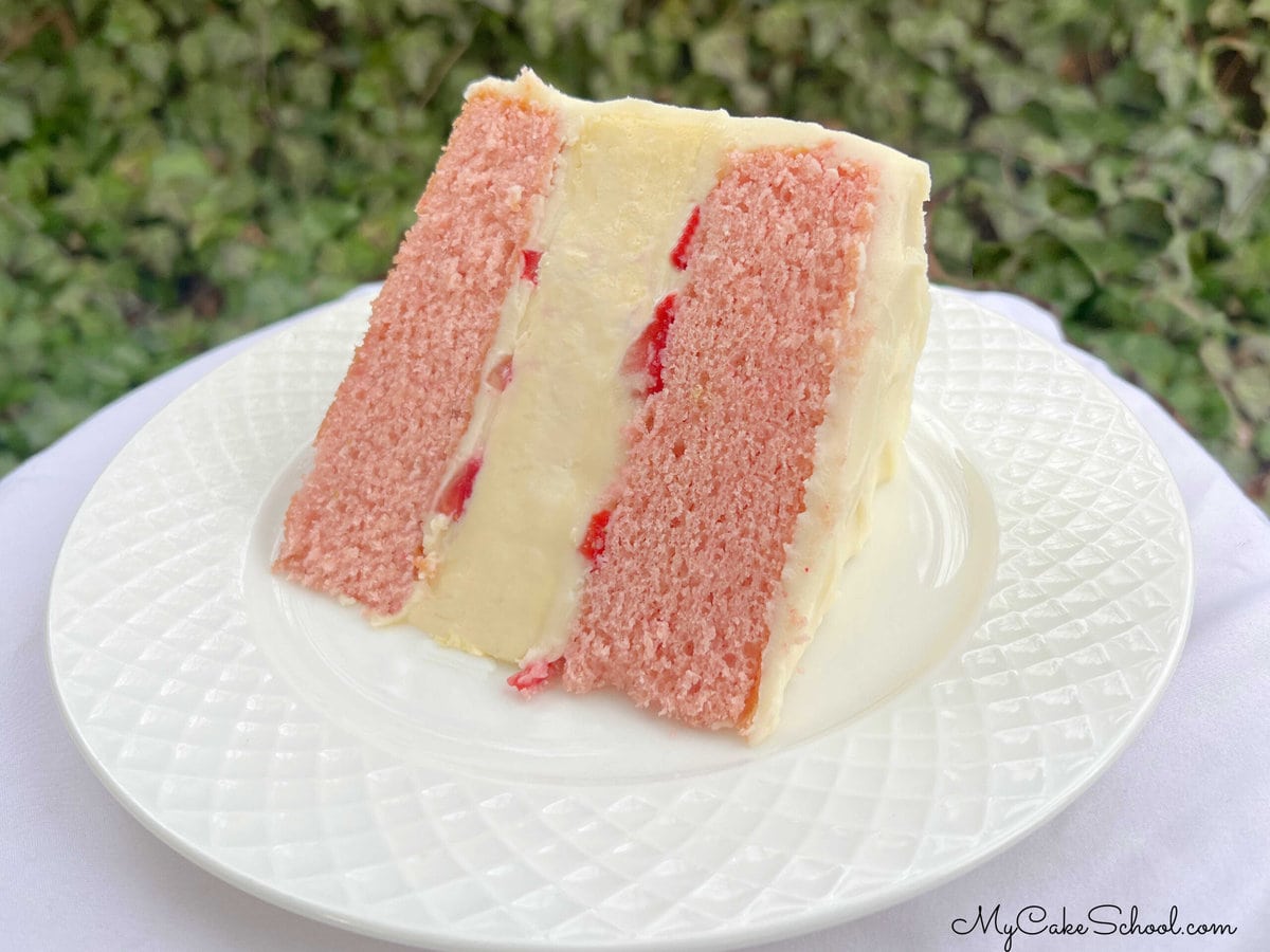Slice  of Strawberry Cheesecake Cake on a white plate.