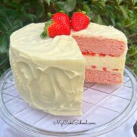 Sliced Strawberry Cheesecake Cake on a cake pedestal.