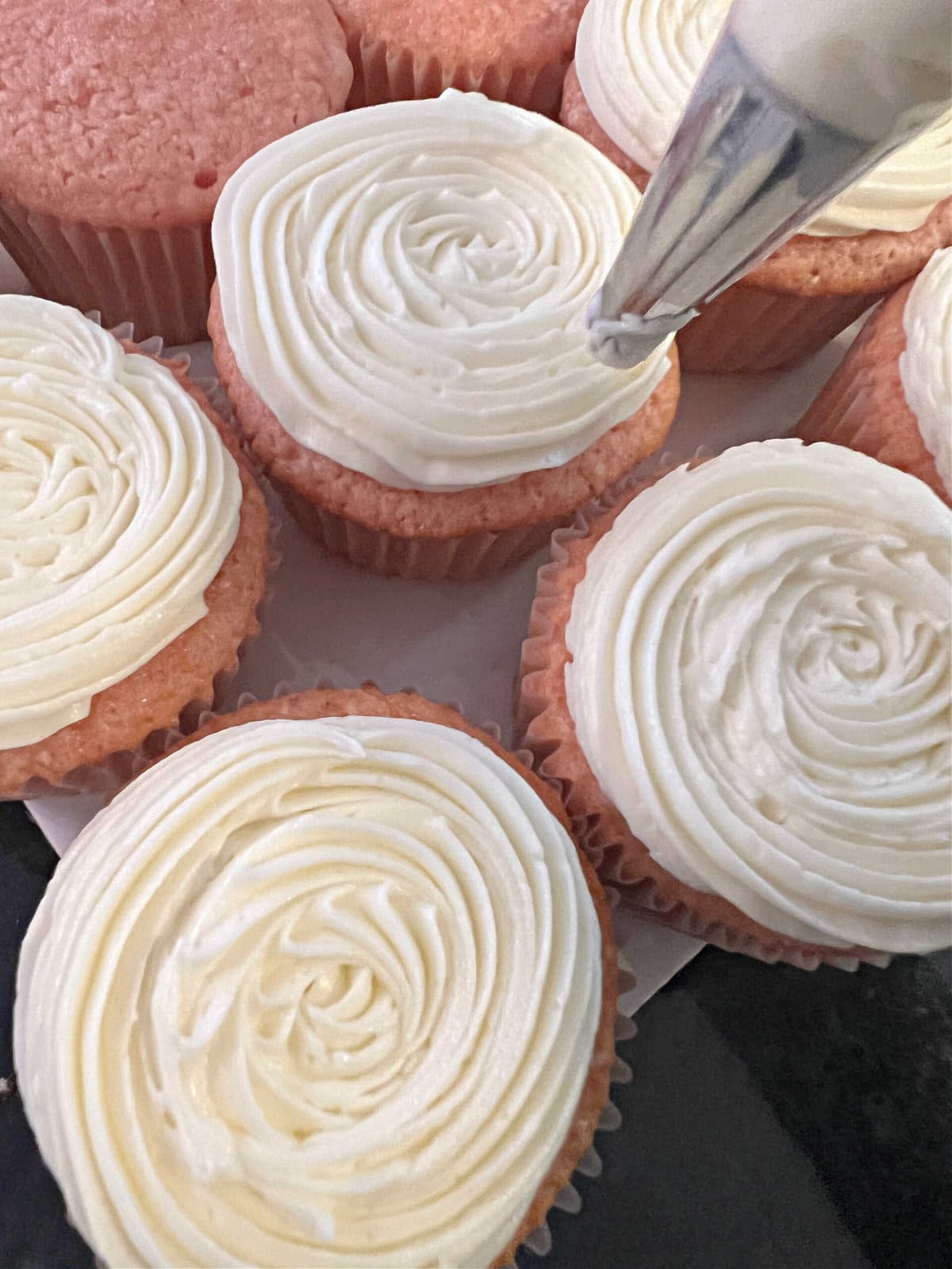 Decorating the cupcakes with a spiral of buttercream, using a star tip 21.