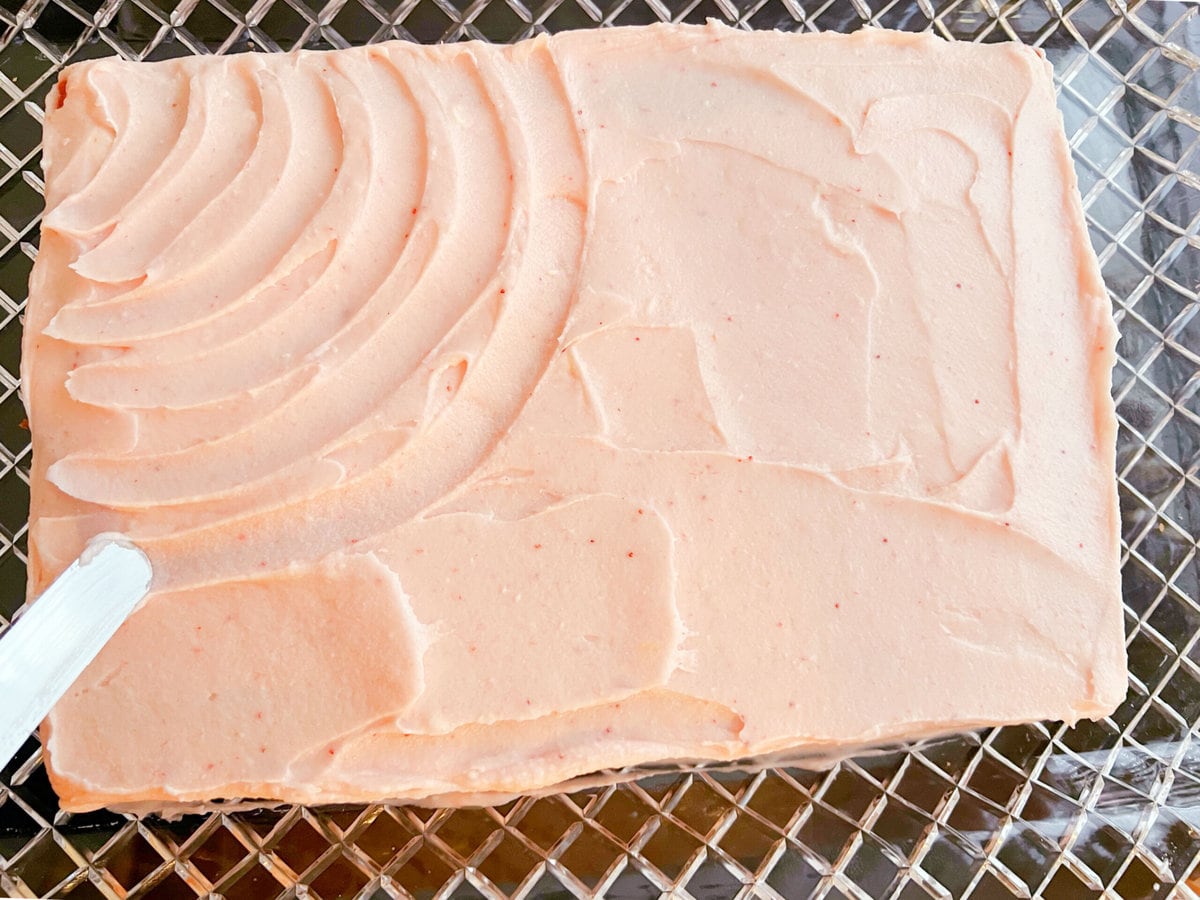 Frosting the top of the strawberry sheet cake.