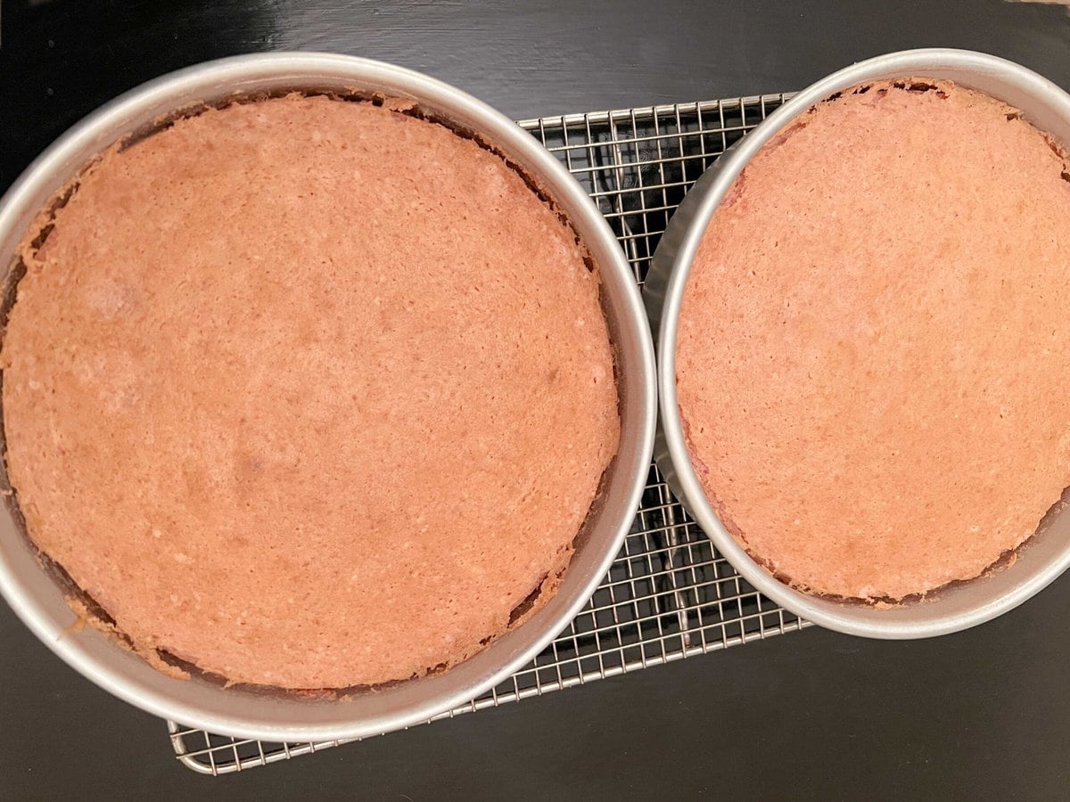 Strawberry Cake Layers, in pans on a cooling rack.