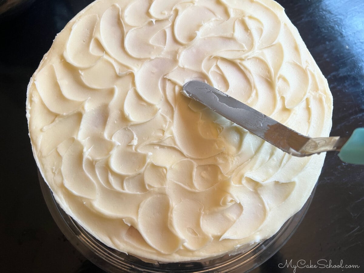 Texturing the frosting on the decorated cake using an offset spatula.