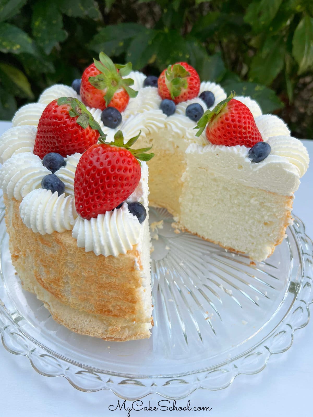 Angel Food Cake, sliced, and topped with strawberries, blueberries,  and whipped cream.