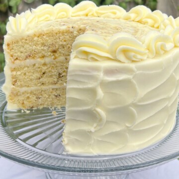 Pistachio cake on a cake pedestal, sliced.