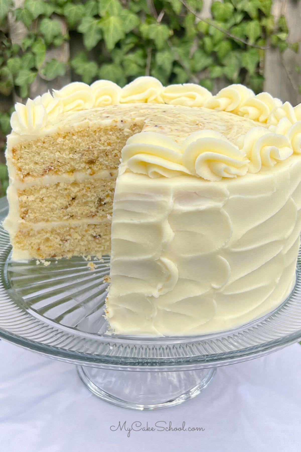 Pistachio cake on a cake pedestal, sliced.
