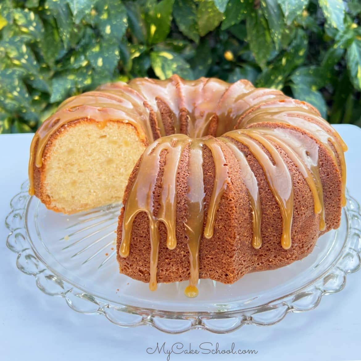 Sliced pear bundt cake on a cake pedestal, topped with caramel glaze.