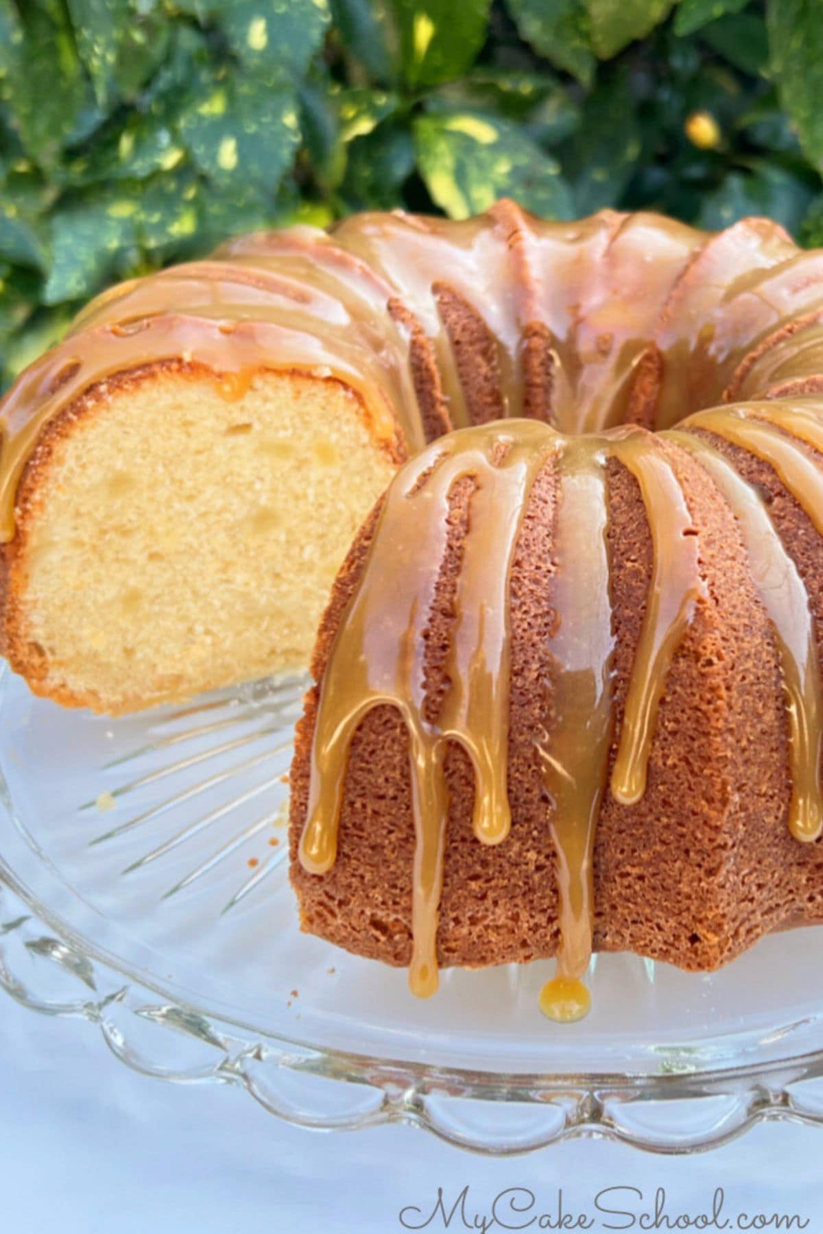 Sliced pear bundt cake on a cake pedestal with caramel glaze.