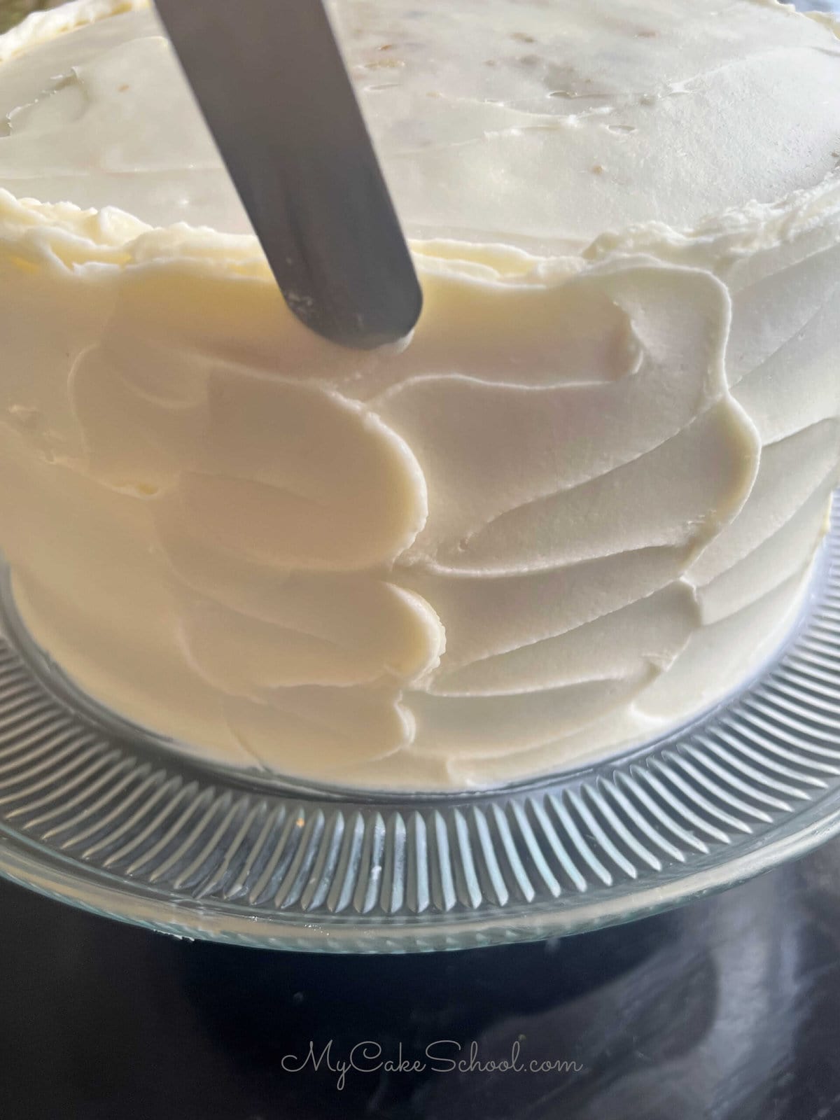 Adding texture to the frosted cake with a small offset spatula.