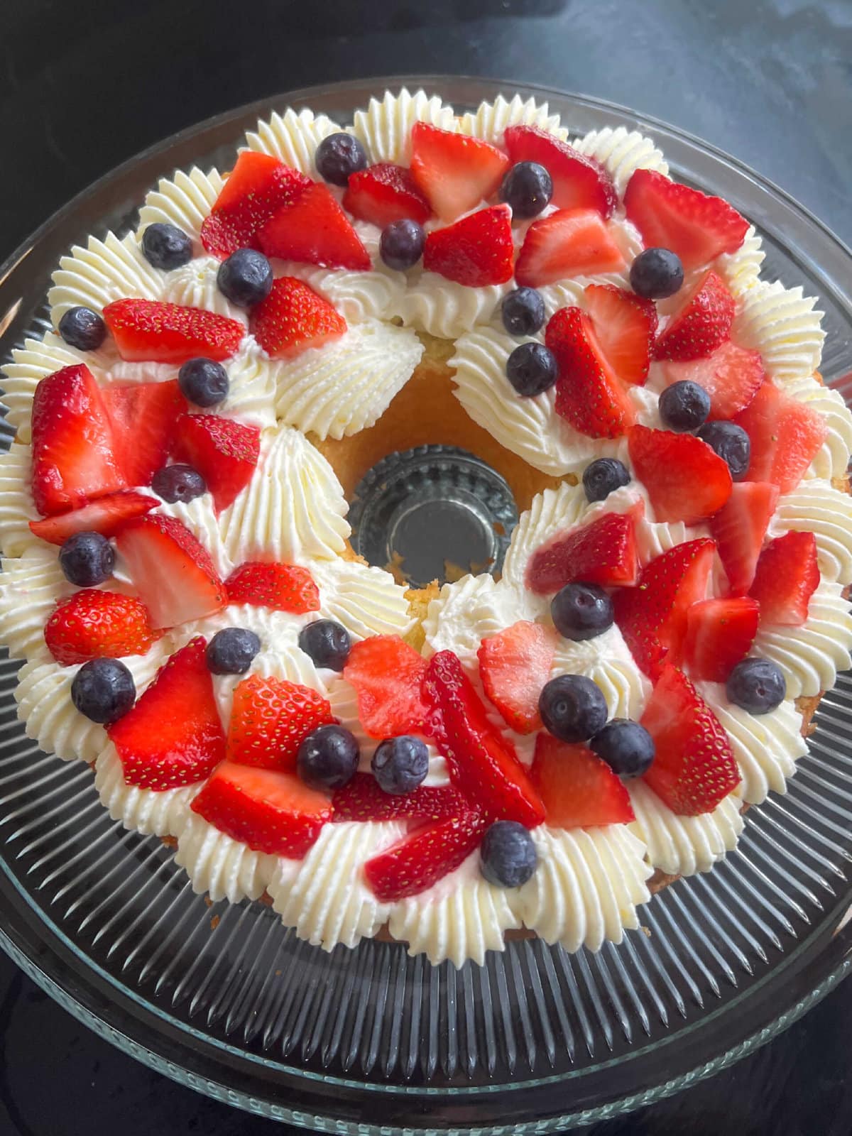 Berries layered onto lemon whipped cream cheese frosting, on top of the bottom layer of cake.