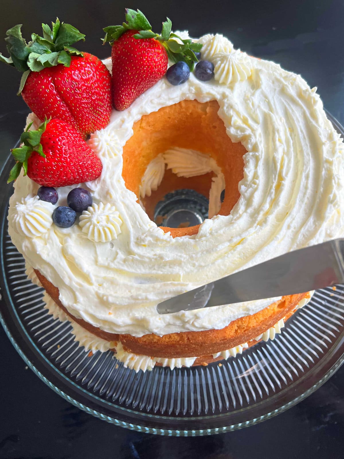 Decorating the Lemon Berry Cake with whipped cream cheese frosting and fresh berries.