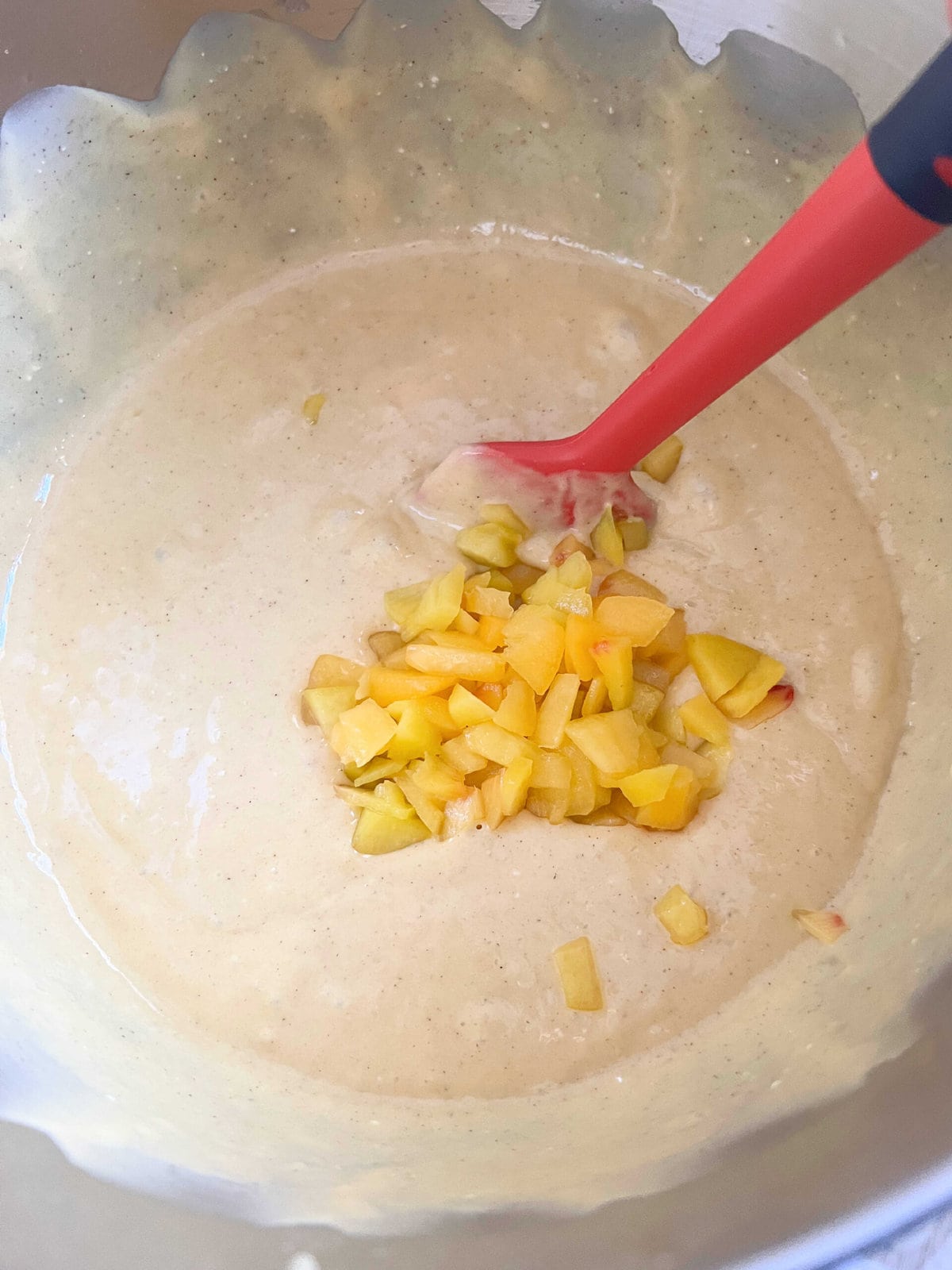 Folding finely chopped peaches into cake batter.
