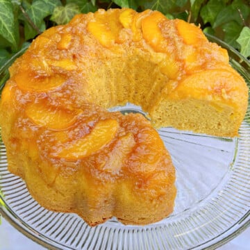 Peach Upside Down Cake, sliced, on a cake pedestal.