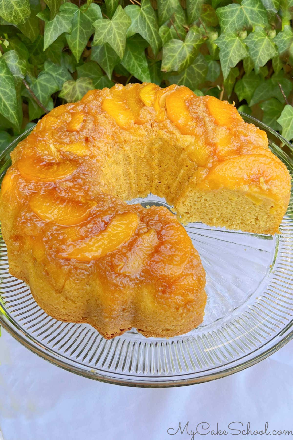 Peach Upside Down Cake, sliced, on a cake pedestal.