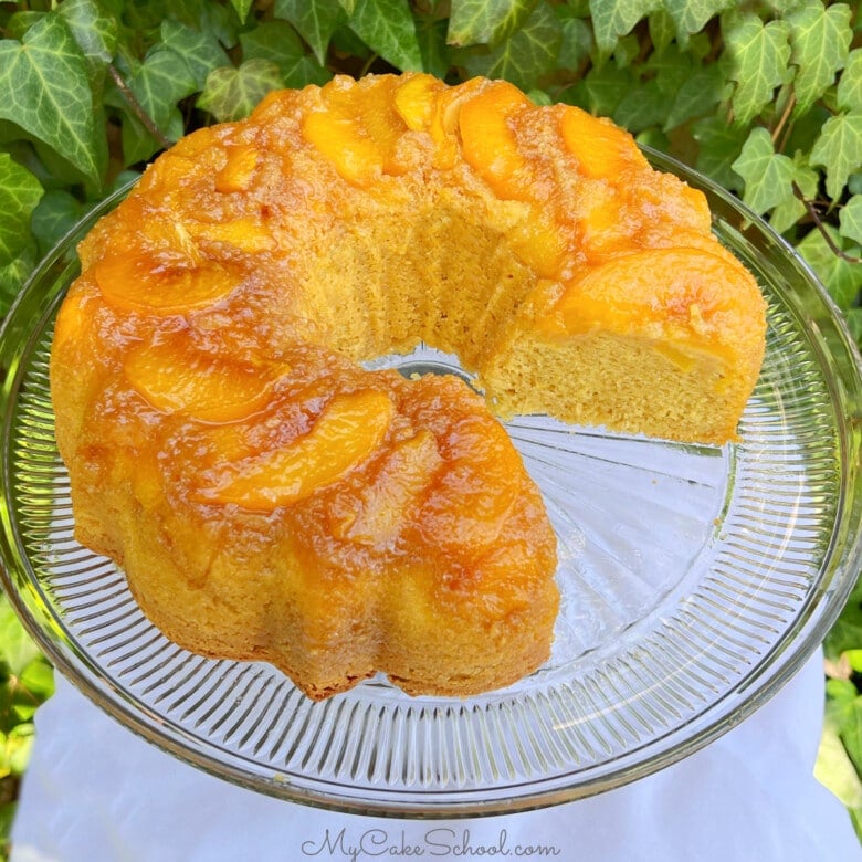 Peach Upside Down Cake, sliced, on a cake pedestal.