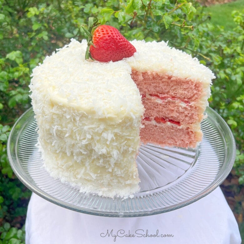 Strawberry Coconut Cake, sliced, on a pedestal.
