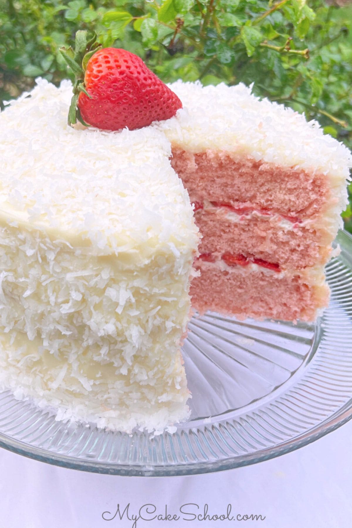 Strawberry Coconut Cake, sliced, on a cake pedestal.